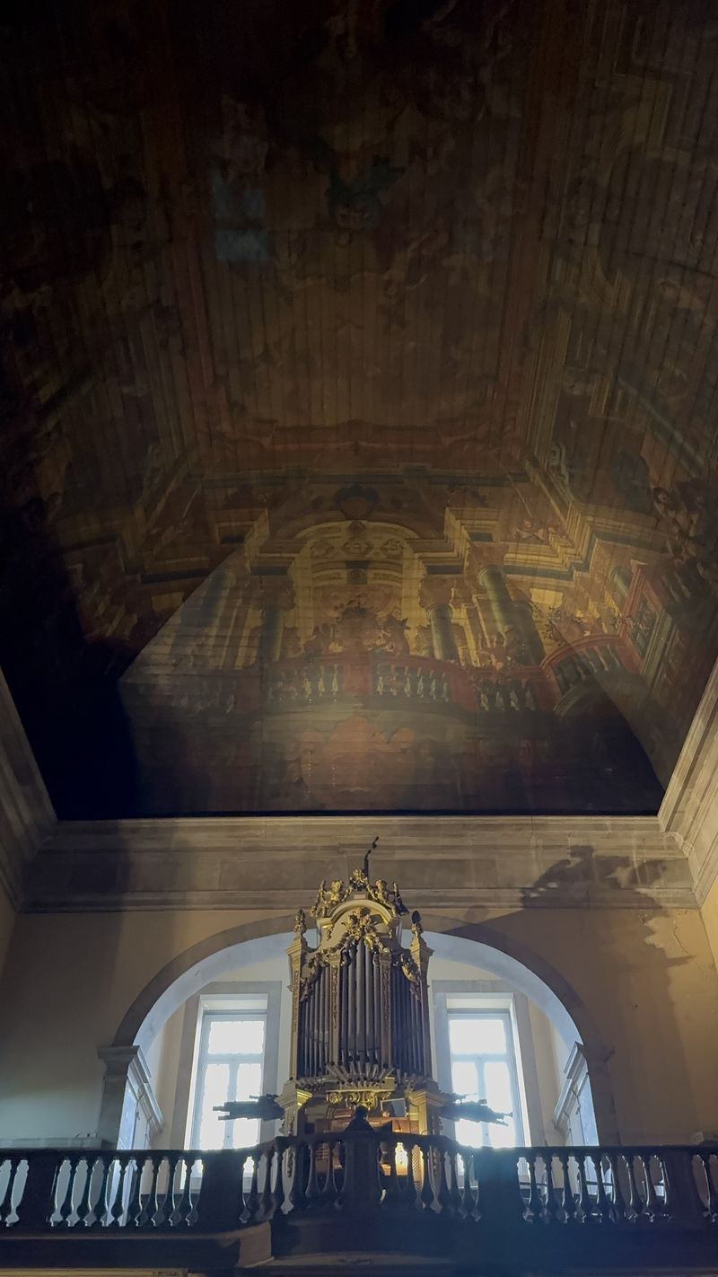 Tecto pintado da Igreja de Nossa Senhora da Pena ao fim do dia, com o órgão no coro alto